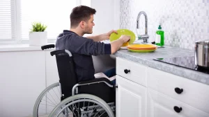 man in wheelchair washing dishes in accessible kitchen design
