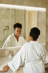black woman using lit LED mirrored cabinet in bathroom design